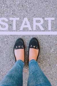 A line with START written above and a person's legs and black shoes, with toes at the line.